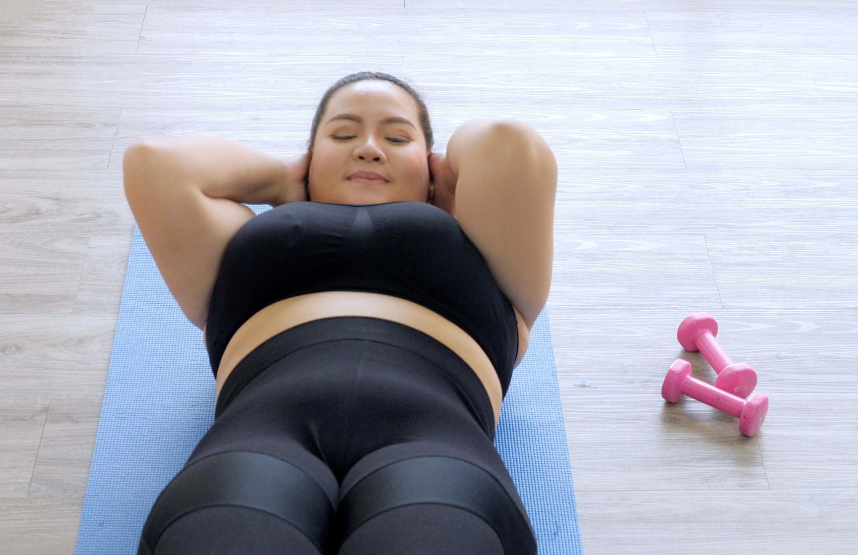 Woman on a blue yoga mat doing sit-ups 