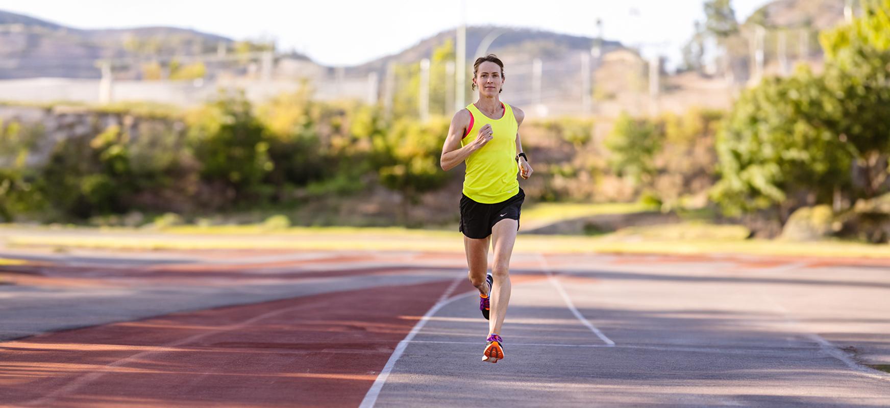 Malindi Elmore in a yellow tank top and black shorts running on a track. Elmore speaks on gender equity in sports.