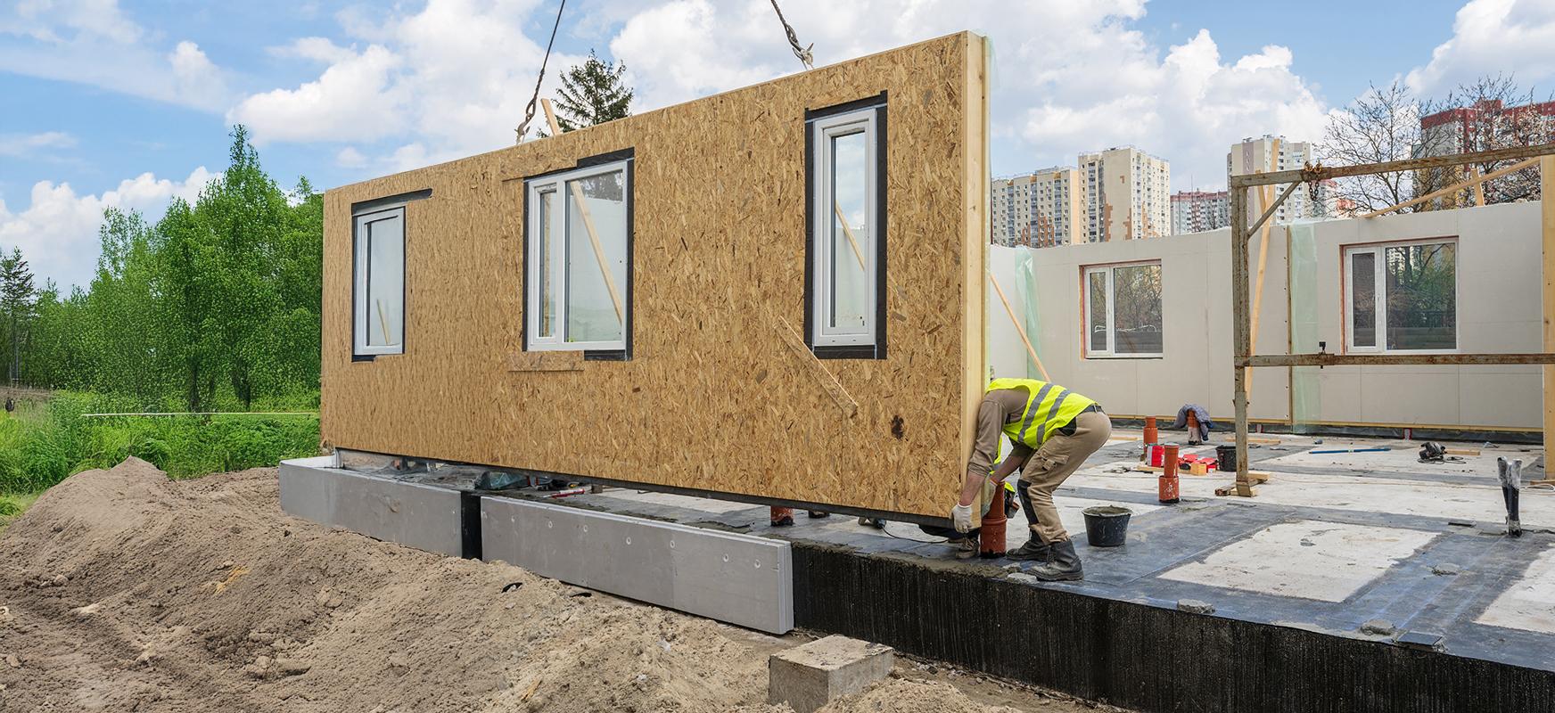 Process of construction new and modern modular house from composite sip panels. Worker man in special protective uniform wear working on building development industry of energy efficient property.