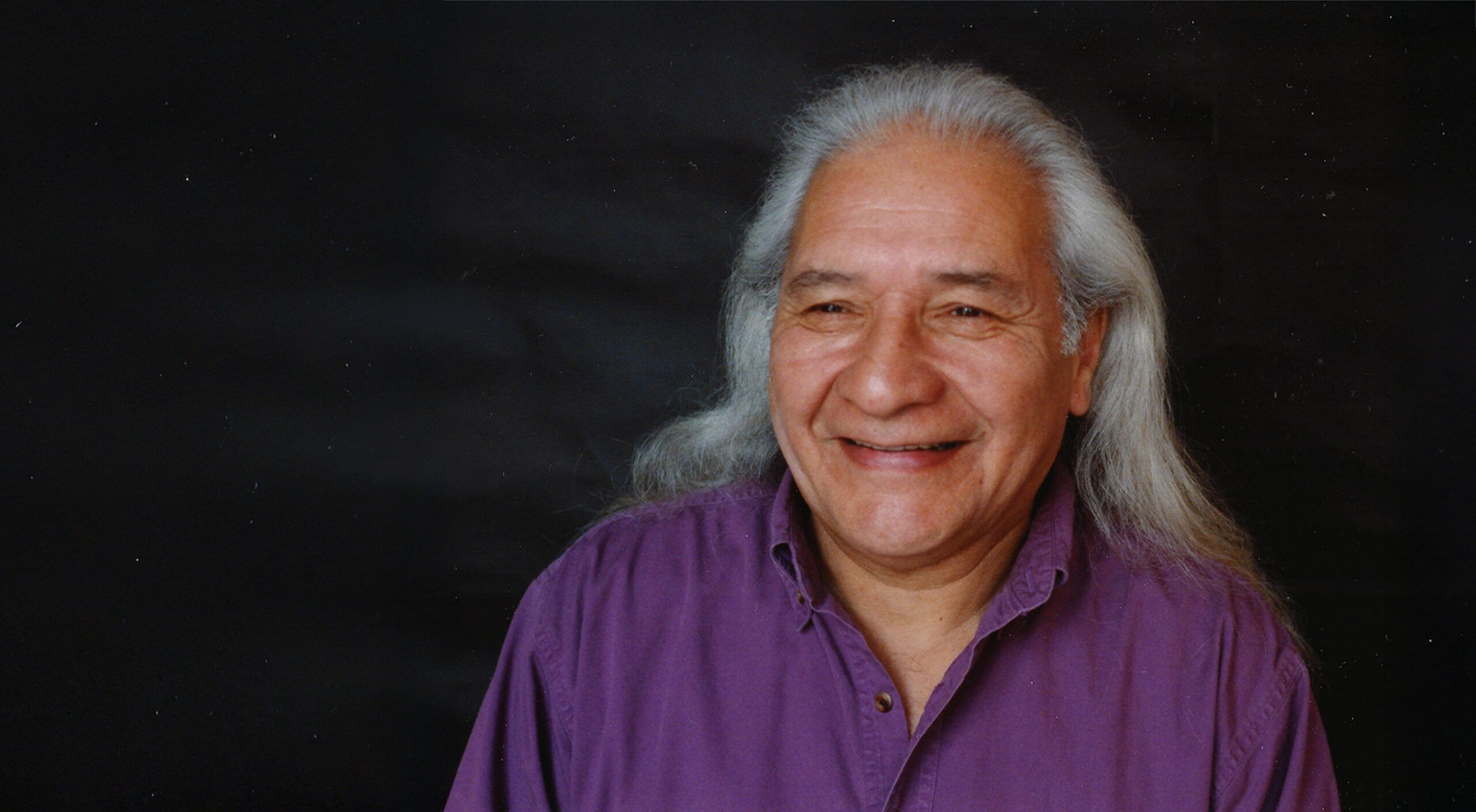 Portrait of Larry Loyie smiling in purple