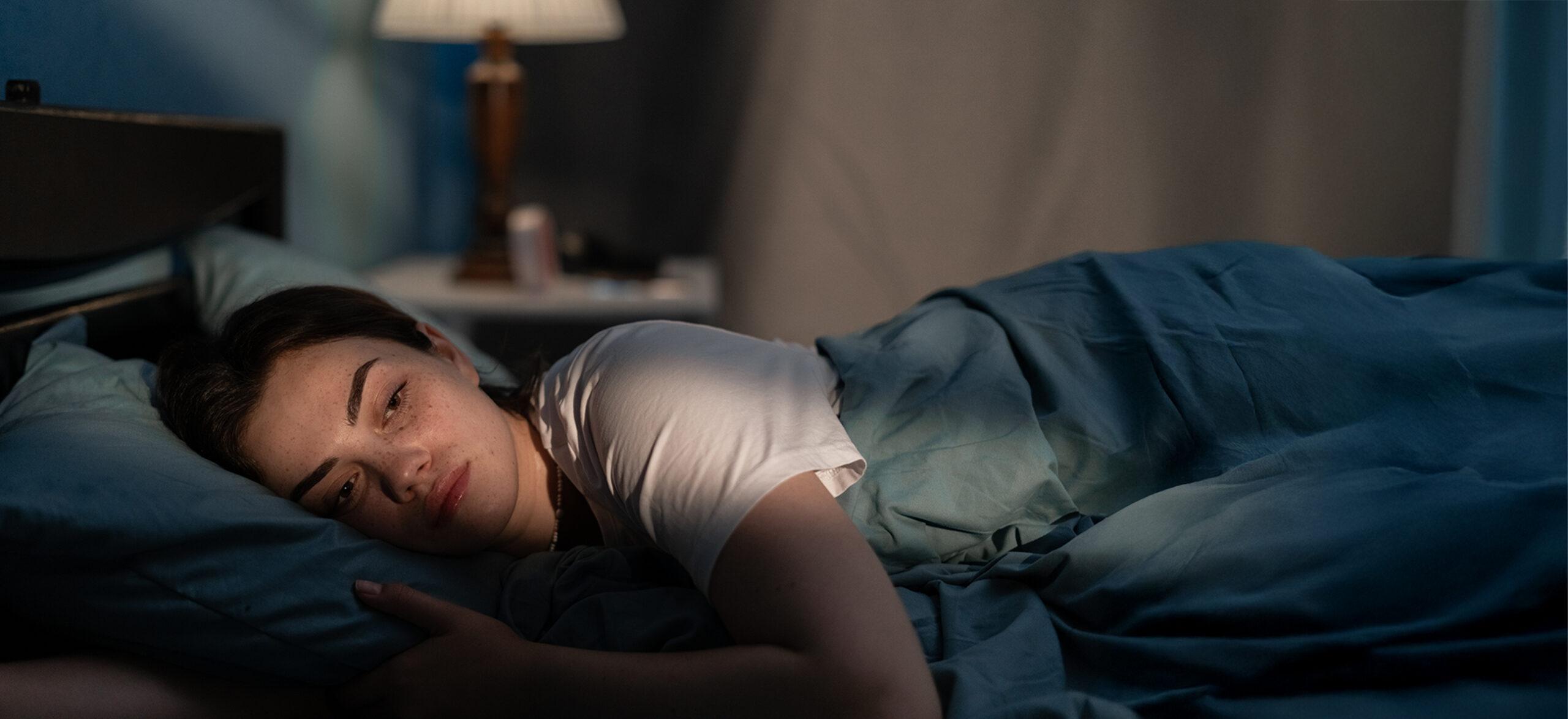 A young woman in bed looking worried and stressed