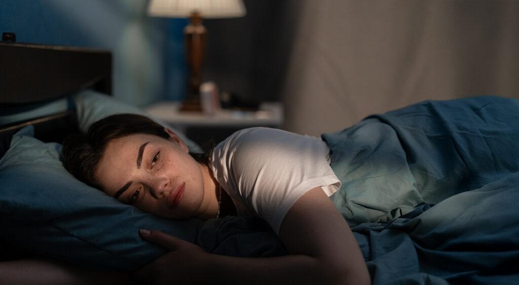A young woman in bed looking worried and stressed