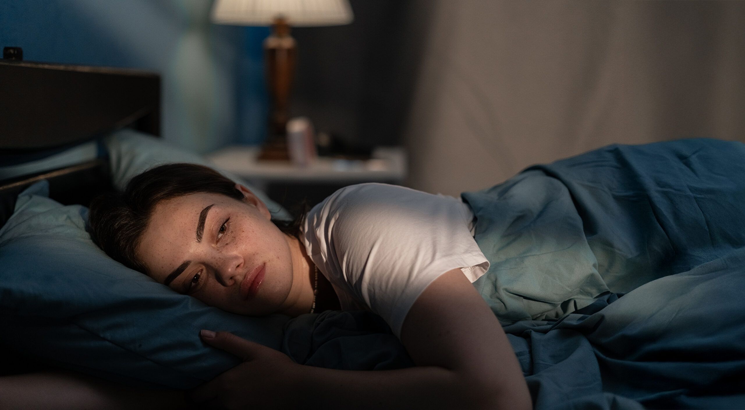 A young woman in bed looking worried and stressed