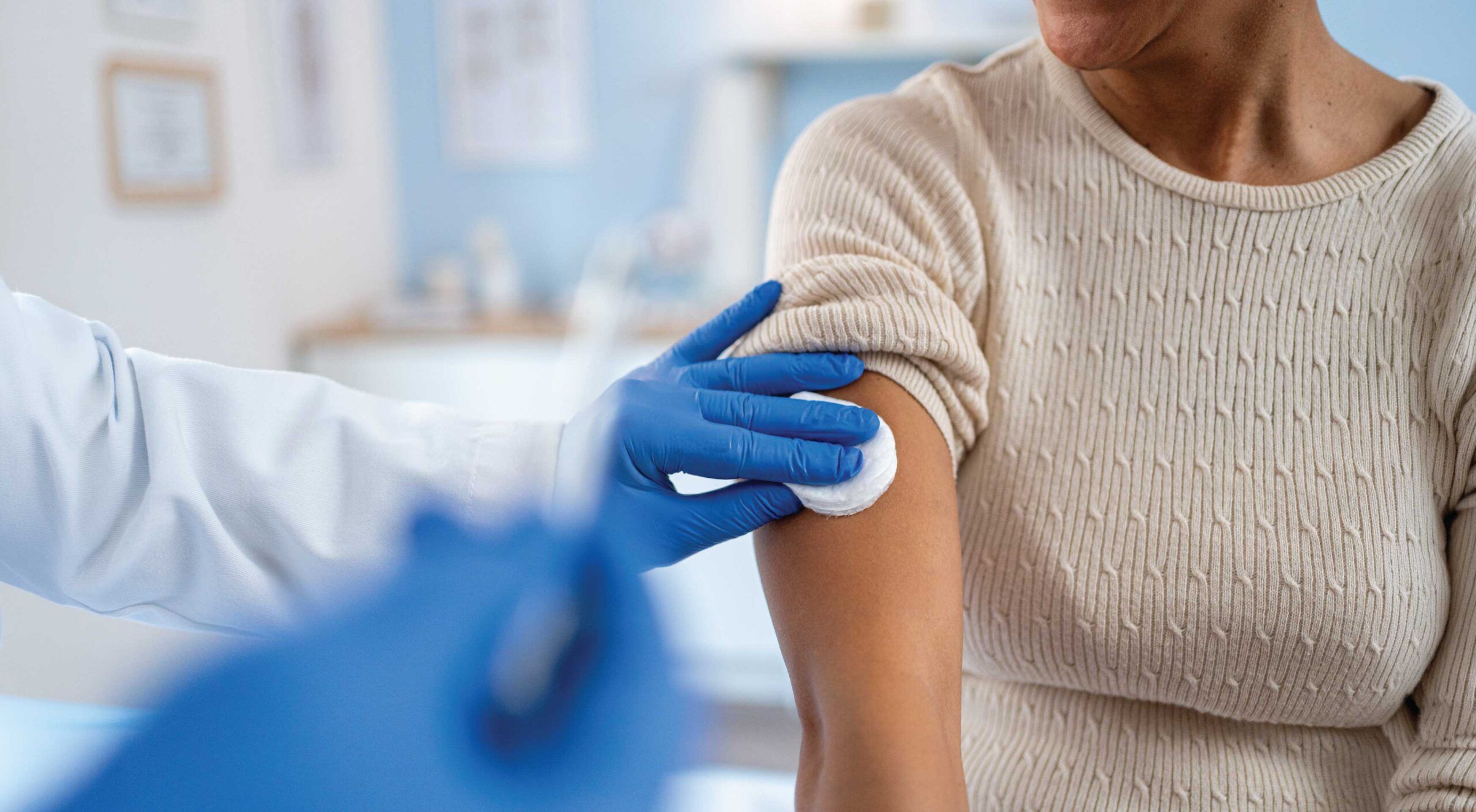 A woman getting a vaccine shot in her arm in a clinic